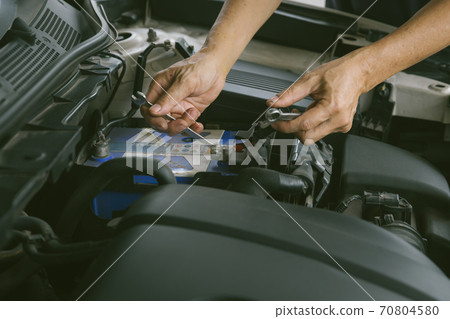 Engine engineer is replacing car battery because car battery is depleted. Engine engineer is replacing car battery because car battery is depleted. 70804580