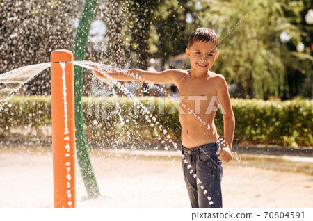 Little boy play on water playground in summer park 70804591