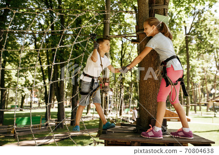 Little kids climbs on net in rope park, playground 70804638