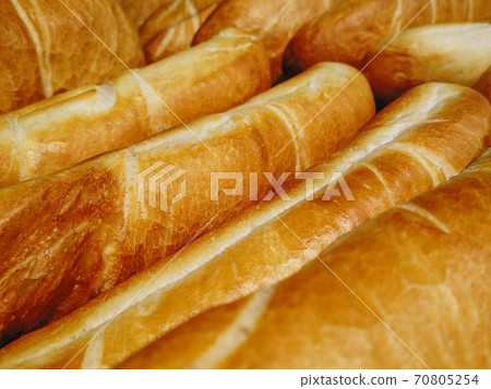 French crispy loaves of baguette pastry background. Long loaf in rows at the bakery shop. French crispy loaves of baguette pastry background. Long loaf in rows at the bakery shop. 70805254