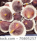 Group of purple fig fruits are on the white paper napkin tartlets decoration. Macro figs view in a circle. Ripe dark blue exotic fruits background. 70805257