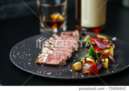 Beef tagliata with potatoes and tomatoes and herbs 70806842