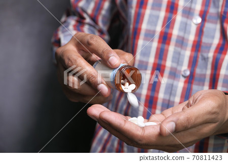 Close up of man hand taking medicine  70811423