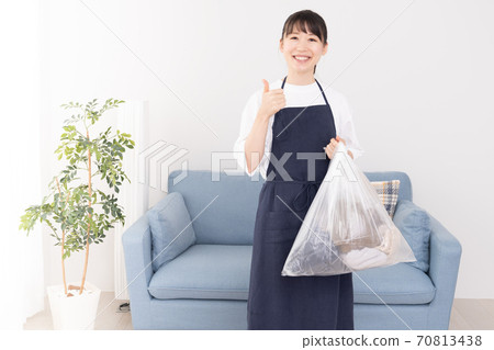 Young woman holding a trash bag in one hand 70813438