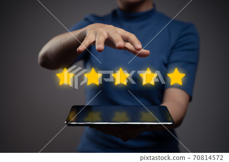 Woman showing tablet present five stars icon hologram effect. Woman showing tablet present five stars icon hologram effect. 70814572