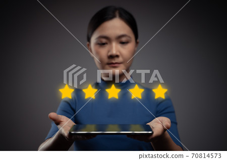 Woman showing tablet present five stars icon hologram effect. Woman showing tablet present five stars icon hologram effect. 70814573