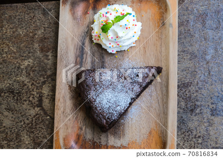 Brownie dark chocolate cake with white cream on wood table 70816834