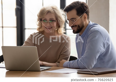 Smiling diverse colleagues work on laptop at meeting 70820925