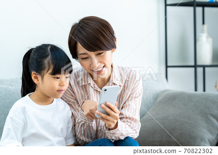 父母和孩子（母子）在客廳裡看著智能手機時放鬆 70822302