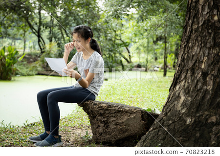 Sad asian child girl sit alone and crying,reading letter,bad news,female teenage student received school notice letter to her about her academic performance slump,disappointed with her education 70823218