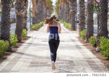Jogging woman on the street of tropical town Jogging woman on the street of tropical town 70823301