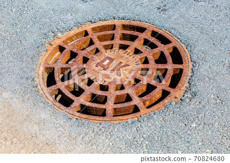 Rusty metal manhole cover on the asphalt road Rusty metal manhole cover on the asphalt road 70824680