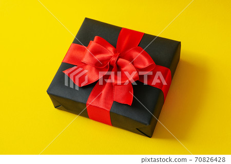Gift box with red bow on yellow background 70826428