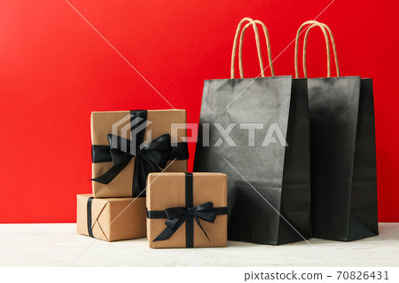 Gift boxes and paper bags against red background Gift boxes and paper bags against red background 70826431