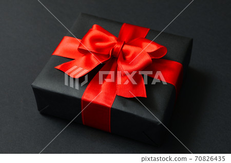 Gift box with red bow on black background Gift box with red bow on black background 70826435