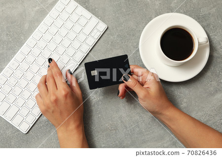 Female hand hold card on gray background with keyboard and coffee Female hand hold card on gray background with keyboard and coffee 70826436