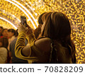 Woman take friend photo by mobile phone under light decoration dome background for Christmas xmas and new year celebration. 70828209