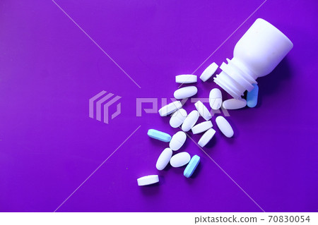 Close up of many pills spilling on color background  70830054