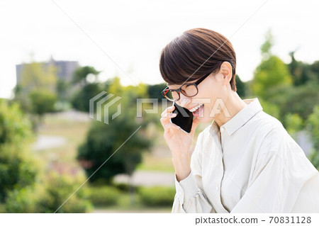 一個女人在陽台上俯瞰一個鬱鬱蔥蔥的公園 70831128