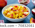 Chopped peaches and whole peache on a  table,  closeup. 70832081
