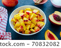 Chopped peaches and whole peache on a  table,  closeup. 70832082