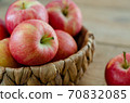 Red apples are in the basket on wooden table 70832085