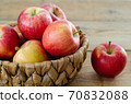Red apples are in the basket on wooden table 70832088