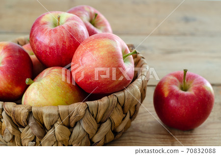 Red apples are in the basket on wooden table 70832088