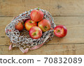 Red apples are in fishnet on wooden table 70832089