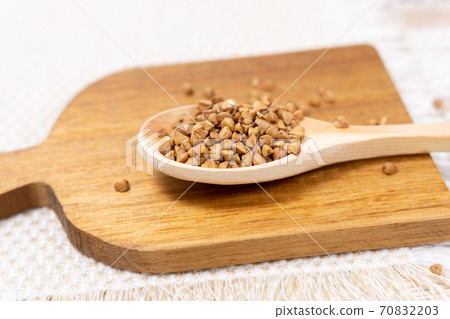 raw buckwheat grain on a wooden spoon on wood table background. selective focus 70832203