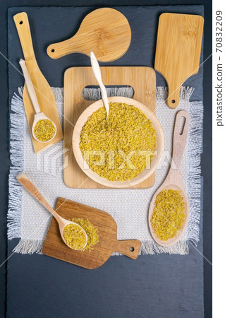 bulgur with a spoon in which bulgur, on a black background. vertical photo bulgur with a spoon in which bulgur, on a black background. vertical photo 70832209