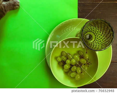 Served wooded table with green wine glass on a green plate with grape 70832948