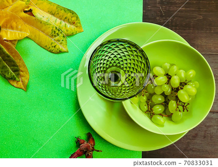 Served wooded table with green wine glass on a green plate with grape 70833031