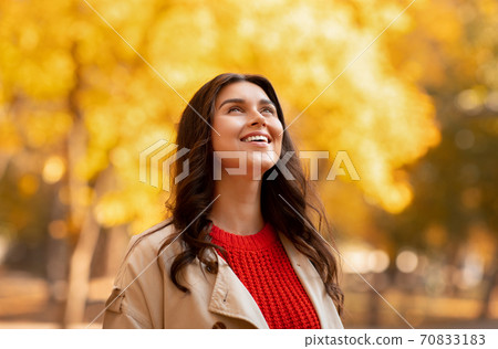 Portrait of gorgeous young woman in autumn outfit smiling and looking up on walk at park Portrait of gorgeous young woman in autumn outfit smiling and looking up on walk at park 70833183