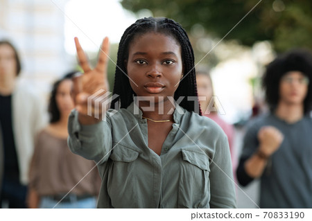 Black woman leading group of international protestors, showing peace gesture Black woman leading group of international protestors, showing peace gesture 70833190