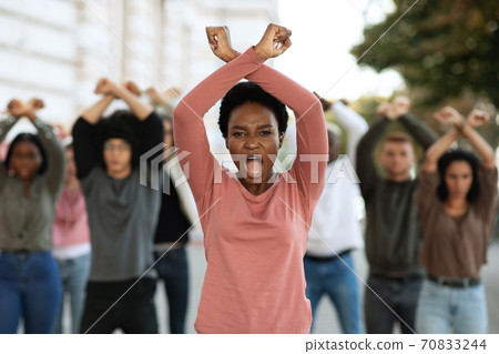 Woman with clenched fists above head protesting with group Woman with clenched fists above head protesting with group 70833244