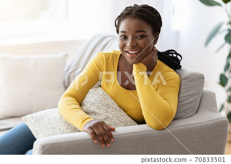 Cheerful African Lady Relaxing On Couch, Holding Pillow And Smiling At Camera 70833501