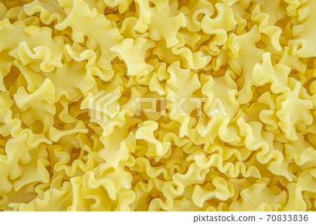 Italian dry wavy pasta background. Healthy traditional food. Top view. Macro close-up 70833836