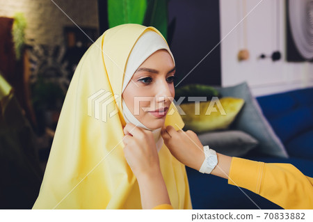 Portrait of a beautiful, elegant and attractive young Malay Asian Muslim woman in a dress and an hijab head scarf. Portrait of a beautiful, elegant and attractive young Malay Asian Muslim woman in a dress and an hijab head scarf. 70833882