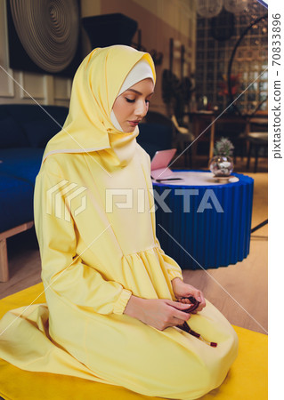Muslim woman in hijab praying on mat indoors. Muslim woman in hijab praying on mat indoors. 70833896
