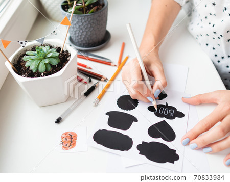 Woman writes Boo! on decorative black stickers for flower pots. Handmade decorations for Halloween. Woman writes Boo! on decorative black stickers for flower pots. Handmade decorations for Halloween. 70833984