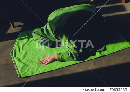 Muslim woman in hijab praying on mat indoors. 70833985