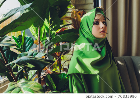Portrait of a beautiful, elegant and attractive young Malay Asian Muslim woman in a dress and an hijab head scarf. 70833986