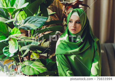 Portrait of a beautiful, elegant and attractive young Malay Asian Muslim woman in a dress and an hijab head scarf. Portrait of a beautiful, elegant and attractive young Malay Asian Muslim woman in a dress and an hijab head scarf. 70833994