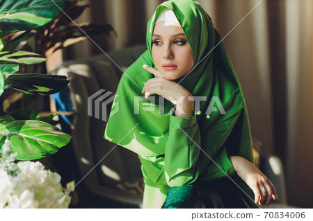 Portrait of a beautiful, elegant and attractive young Malay Asian Muslim woman in a dress and an hijab head scarf. Portrait of a beautiful, elegant and attractive young Malay Asian Muslim woman in a dress and an hijab head scarf. 70834006