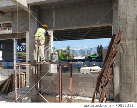 SEREMBAN, MALAYSIA -MARCH 16, 2020: Construction workers laying autoclaved aerated concrete block at the construction site. The use of this material can save time and facilitate construction work. SEREMBAN, MALAYSIA -MARCH 16, 2020: Construction workers laying autoclaved aerated concrete block at the construction site. The use of this material can save time and facilitate construction work. 70835331