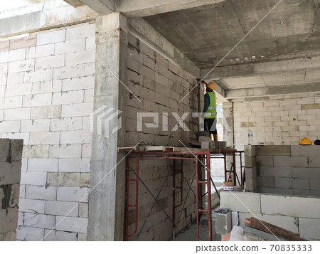 SEREMBAN, MALAYSIA -MARCH 16, 2020: Construction workers laying autoclaved aerated concrete block at the construction site. The use of this material can save time and facilitate construction work. SEREMBAN, MALAYSIA -MARCH 16, 2020: Construction workers laying autoclaved aerated concrete block at the construction site. The use of this material can save time and facilitate construction work. 70835333