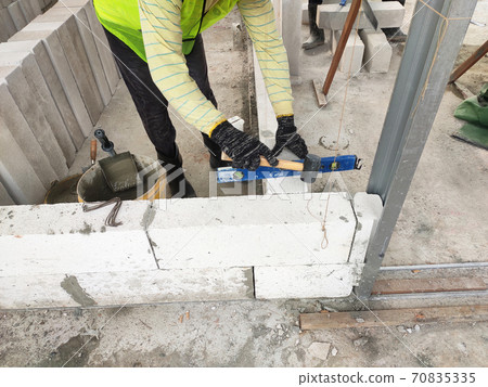 SEREMBAN, MALAYSIA -MARCH 16, 2020: Construction workers laying autoclaved aerated concrete block at the construction site. The use of this material can save time and facilitate construction work. SEREMBAN, MALAYSIA -MARCH 16, 2020: Construction workers laying autoclaved aerated concrete block at the construction site. The use of this material can save time and facilitate construction work. 70835335