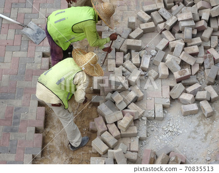 KUALA LUMPUR, MALAYSIA -AUGUST 06, 2017: Construction workers installing and arranging precast concrete pavers stone for a road at the construction site.  70835513