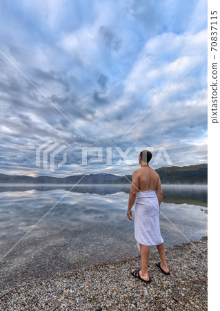 Man standing by water ready to go swimming Man standing by water ready to go swimming 70837115